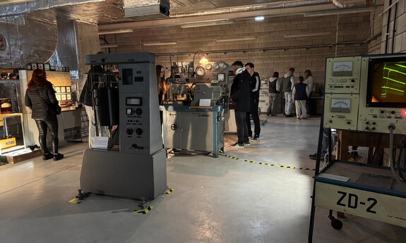 Zwiedzający oglądają ekspozycję zabytkowych urządzeń technicznych w Muzeum Politechniki Lubelskiej. W pomieszczeniu znajdują się m.in. oscyloskopy, tablice kontrolne i maszyny laboratoryjne.